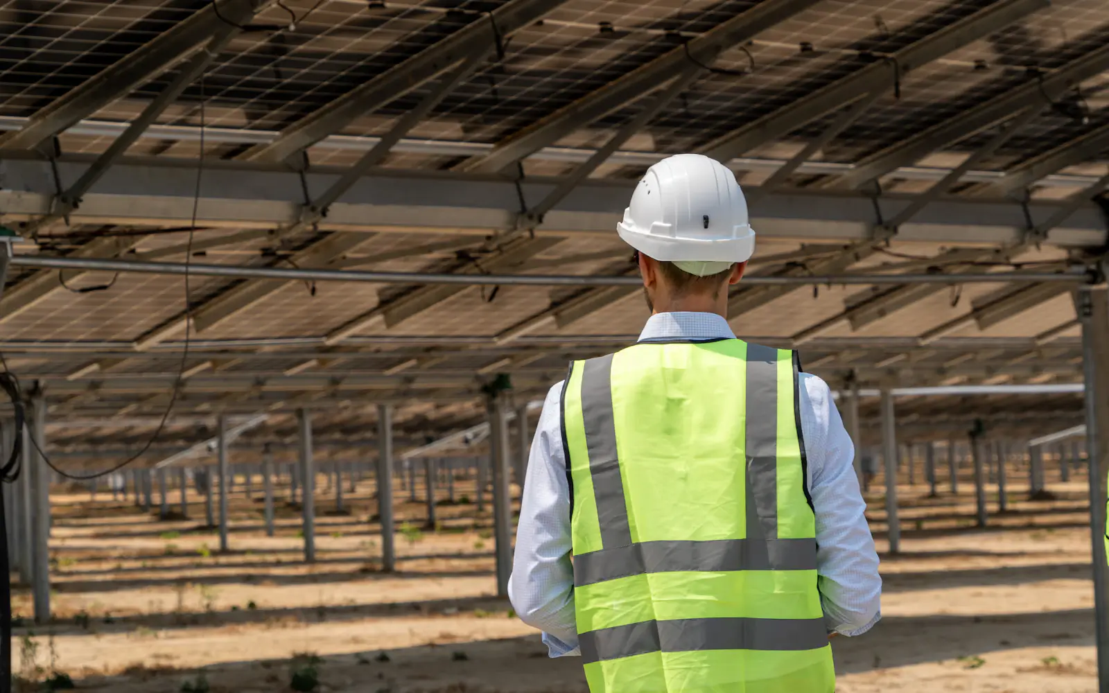 Técnico com capacete e colete de segurança em usina de energia solar fotovoltaica